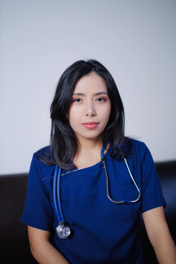 A nurse in navy scrubs with a stethoscope around their neck, facing the camera.