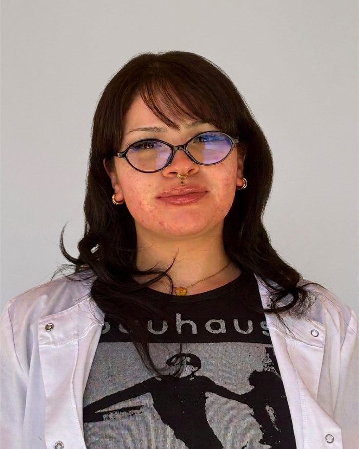 Portrait of Melissa Velasco wearing glasses and a light-colored overshirt.