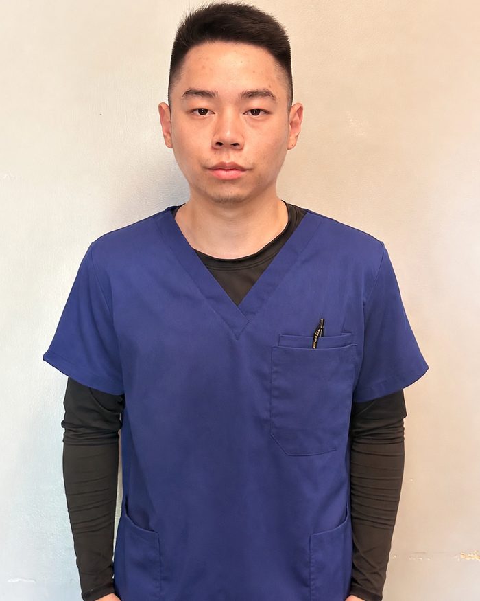 Portrait of Pierre Lam in navy scrubs in a hospital corridor.